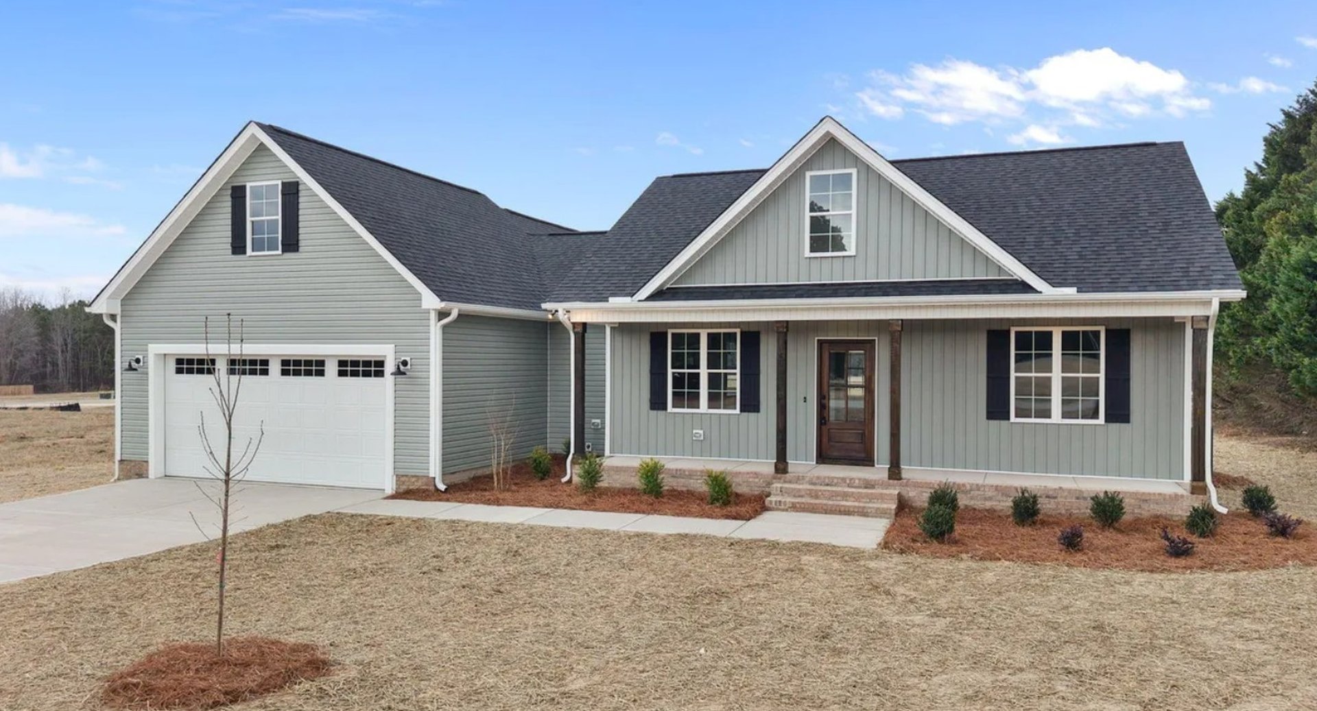 Sage-green craftsman home with new siding, front porch, and two-car garage built by Chapman's Construction